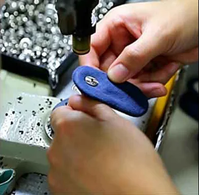 Auto accessory factory worker using a semi-automatic pneumatic machine to install heavy-duty metal snaps and rivet-reinforced handles on collapsible car organizers